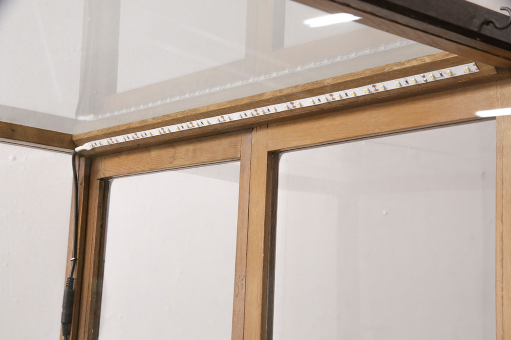 【セミオーダー家具実例】縦型パンケースに高品質リペアを施しました。現状のガラスを綺麗に掃除して取り付け、取っ手は元のものをそのまま使用し、欠品箇所は同様のものを新たに取り付け。下段の扉は上段扉と同様のデザインに製作し、アンティーク加工を!棚板は木製からガラス棚板へ交換。LED照明を上下段の上部に取り付けました。(ガラスケース、ショーケース、陳列棚)